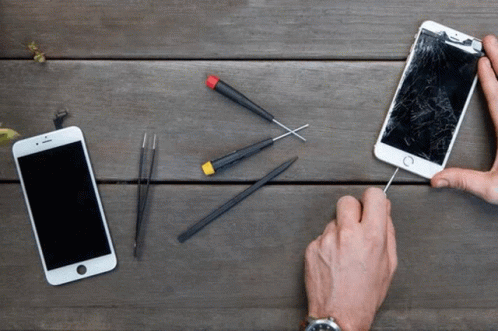 Person Holding Screwdriver Beside Phone With Broken Screen GIF