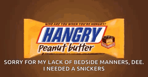 Person Holding Snickers Bar in Front of Computer