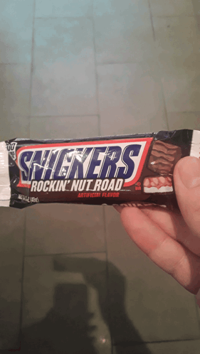 Person Holding Snickers Rockin Nut Road Bar