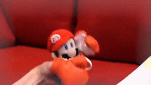 Person Holding Stuffed Mario Doll on Red Couch