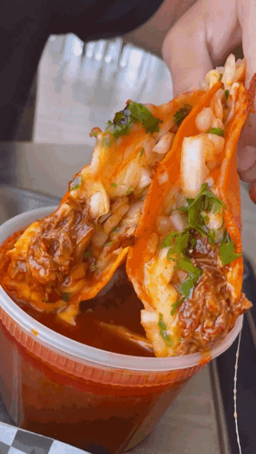 Person Holding Taco Over Sauce