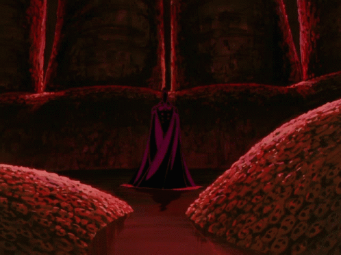 Person in Black Cape Stands in Dark Room