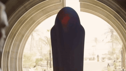 Person in Black Robe in Front of Large Window