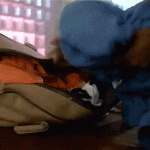 Person in Blue Jacket Looking into Backpack