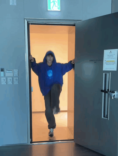 Person In Blue Jacket Standing In Dance Studio Doorway GIF
