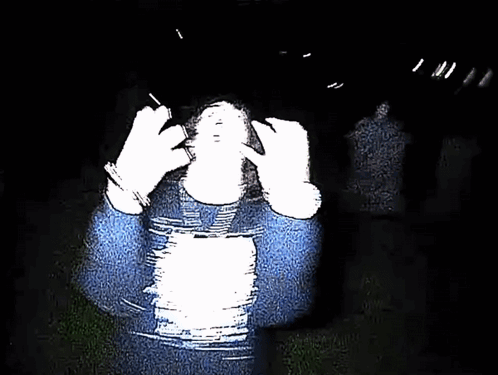 Person in Blue Sweater Covering Face in Dark