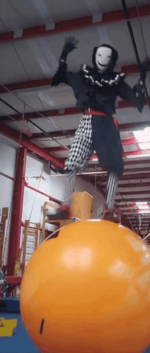 Person in Clown Costume Balancing on Orange Ball