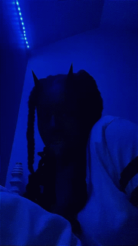 Person In Devil Costume Lying On Bed With Blue Light GIF