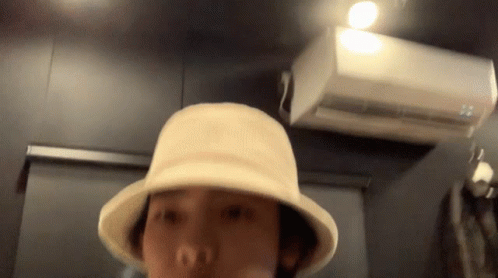 Person in Hat Standing in Front of White Air Conditioner
