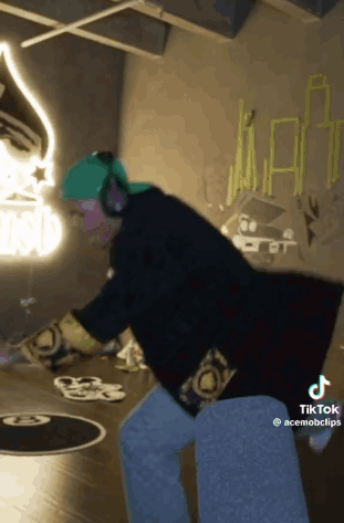 Person in Headphones and Green Hat Dancing in Graffiti Room