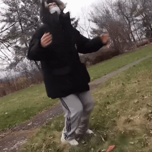 Person in Mask and Black Jacket Dancing in Grass