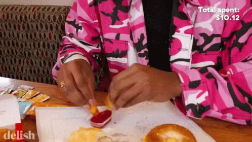Person in Pink Camo Jacket Dipping Fries in Ketchup