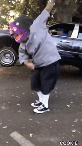 Person in Purple Mask and Beanie Dancing by Car Saying Cookie