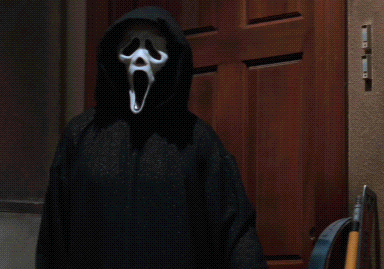 Person in Scream Mask Standing by Wooden Door