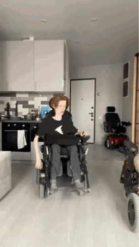 Person In Wheelchair In Kitchen With Scooter GIF