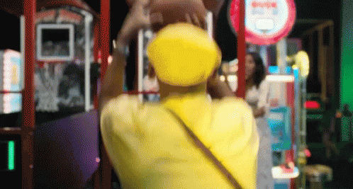 Person In Yellow Hat In Front Of Arcade Sign GIF