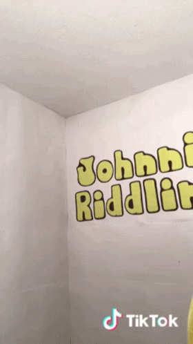 Person in Yellow Shirt in Front of Johnny Riddler Wall