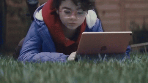 Person Laying in Grass with Laptop Saying Whats a Computer
