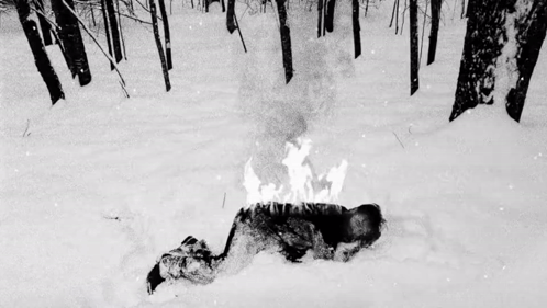 Person Laying in Snow With Fire on Head