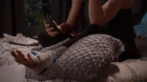 Person Laying On Bed With Bandaged Foot And Cell Phone GIF