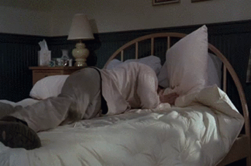 Person Laying on Bed With Pillow on Face