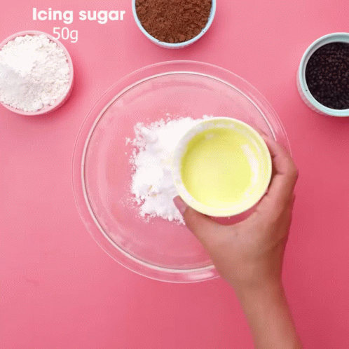 Person Mixing Icing Sugar in Glass Bowl