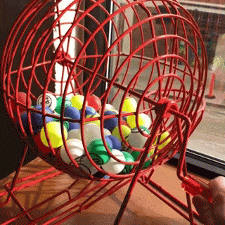 Person Playing Bingo with Red Cage of Balls