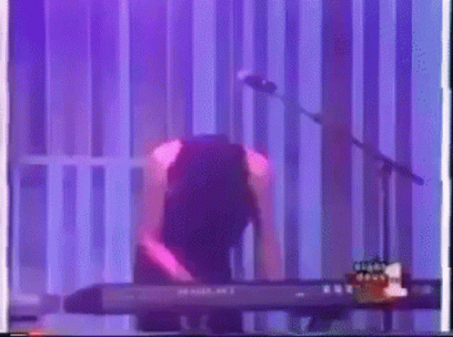 Person Playing Keyboard at Microphone With Purple Light