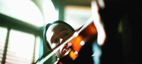 Person Playing Violin in Front of Window