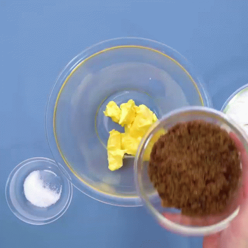 Person Pouring Brown Sugar into Glass Bowl