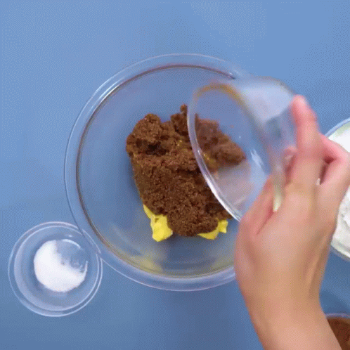 Person Pouring Brown Sugar into Glass Bowl