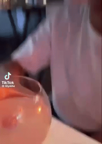 Person Pouring Drink Into Glass With Candle