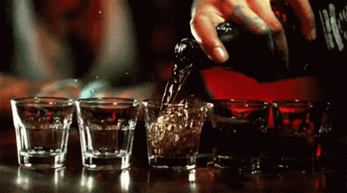 Person Pouring Drink Into Shot Glasses GIF