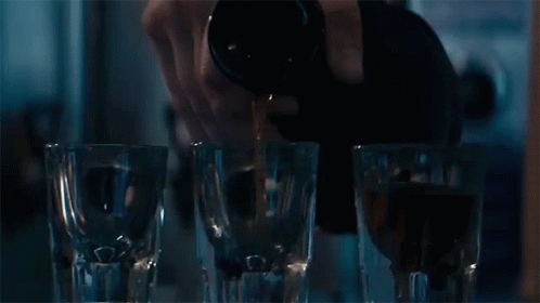Person Pouring Drink Into Shot Glasses GIF