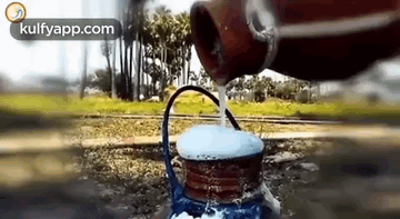 Person Pouring Water from Bottle into Teapot