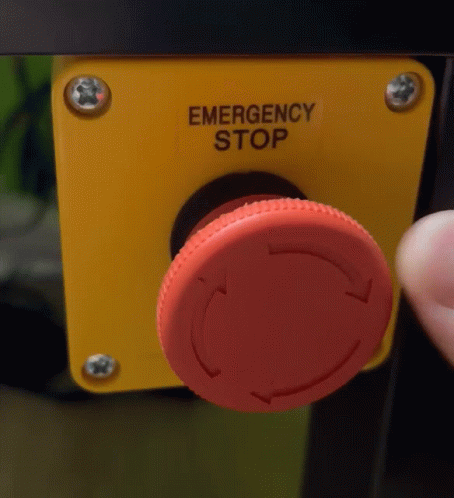 Person Pressing Emergency Stop Button on Yellow Box