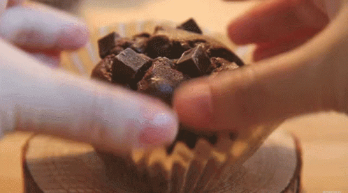 Person Putting Chocolate Chips in Chocolate Cupcake
