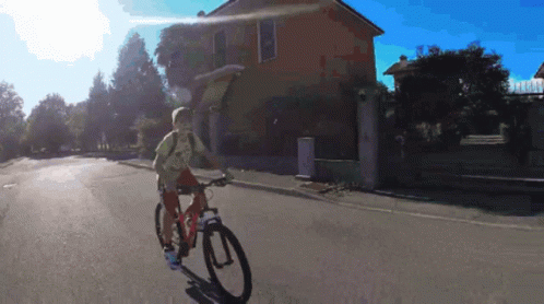 Person Riding Bike Down Street in Front of Building