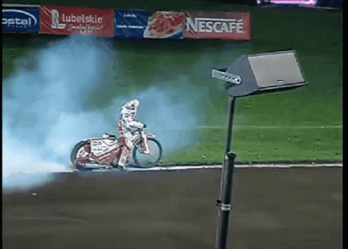 Person Riding Motorcycle On Track With Nescafe Banner GIF