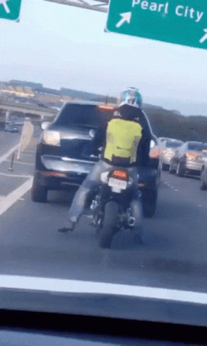Person Riding Motorcycle Past Pearl City Sign
