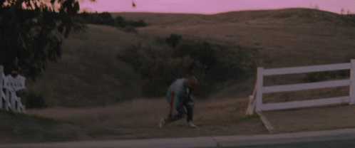 Person Running in Field With Fence