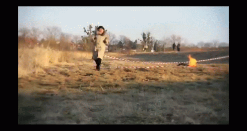 Person Running in Field With Fire Behind