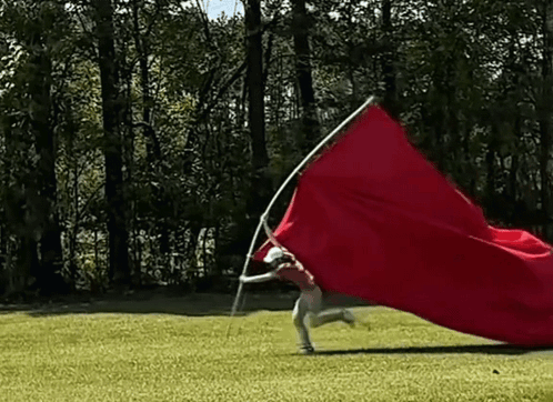Person Running With Red Flag on Pole