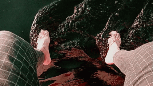 Person's Feet Standing on Rock in Water