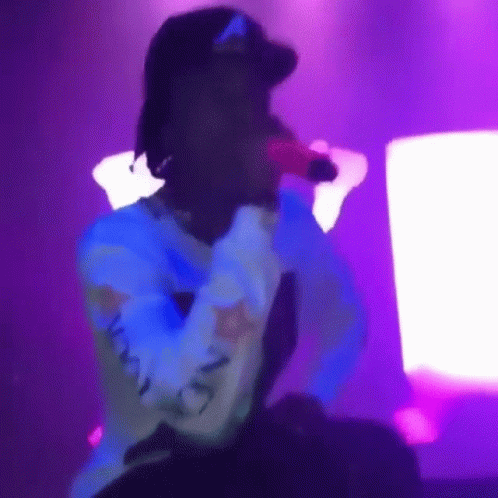 Person Singing Into Microphone on Stage Purple Light