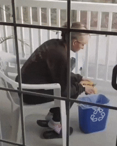 Person Sitting Next to Blue Recycle Trash Can