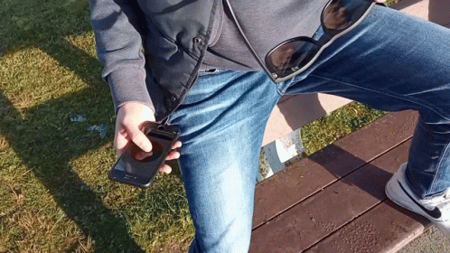 Person Sitting on Bench Holding Phone and Sunglasses