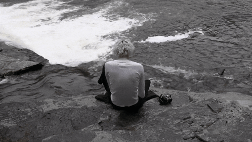 Person Sitting On Rock Near River GIF