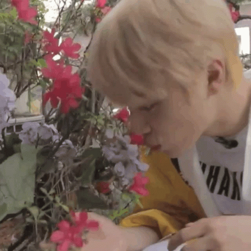 Person Smelling Flowers In Garden GIF