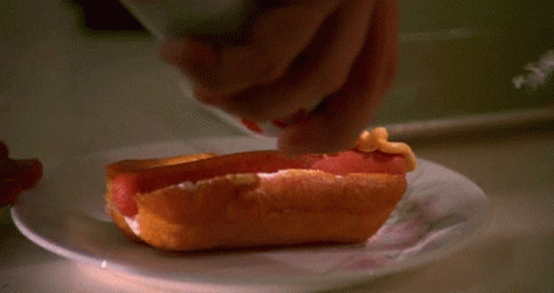 Person Spreading Mustard On Hot Dog